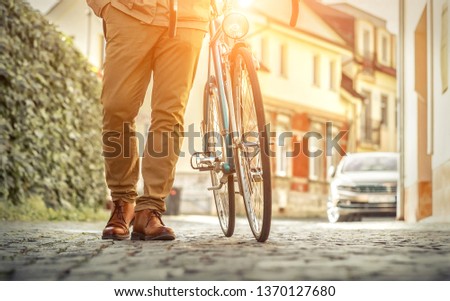 Young stylish businessman go to work with his sport retro bike in sunny day. Business, street concept.