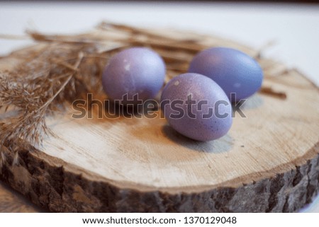 Easter lilac eggs with wheat branches on wooden stand close-up blurred background