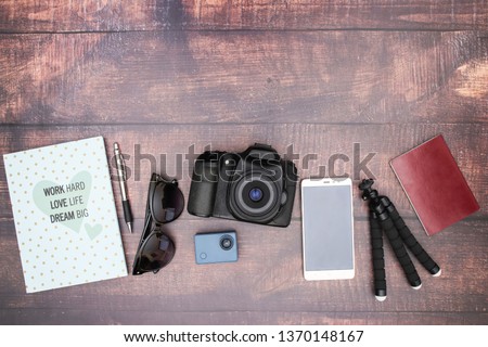 Travel kit, camera, mobile, tripod, notebook and sunglasses on wooden background