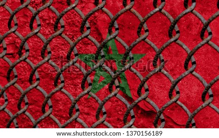 Immigration policy regarding migrants, illegal immigrants and refugees. Steel grid on the background of the flag of Morocco