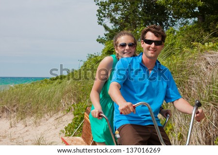 A young couple at the beach sand dunes on a bicycle built for two Royalty-Free Stock Photo #137016269