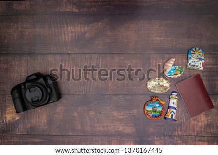 Camera passport and travel magnets on wooden background
