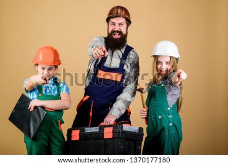 construction worker assistant. Builder or carpenter. Repairman in uniform. Foreman. Family teamwork. Repair. Father and daughter in workshop. Bearded man with little girls. Every detail is important.