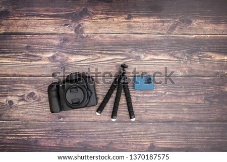 Tripod and camera on wooden background 