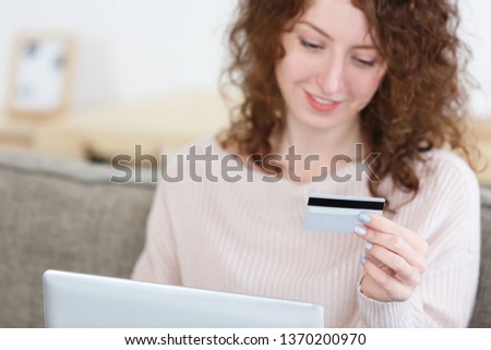 Cropped shot of caucasian female in cozy sweater sitting at home keyboarding on laptop pc, holding credit card, making payment while shopping online. Modern technologies, selective focus