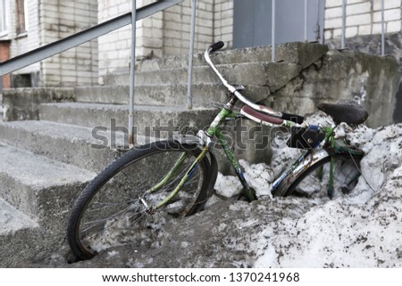 old rusty bike sticks out of the snow on the porch