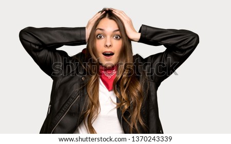 Young woman with leather jacket takes hands on head because has migraine over isolated grey background