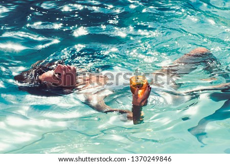cocktail drinking in summer pool. girl drink cocktail from glass Royalty-Free Stock Photo #1370249846