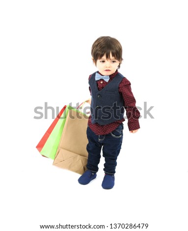 Confident young boy holding different shopping bags against a white background