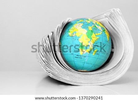 news paper rolled up with globe on a table stock photo