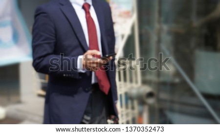 Blurred abstract background, businessman walking and using smartphone  