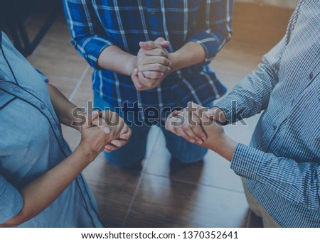 Three christian friends knee down  on floor and prays to God  together indoor, small group fellowship and prays meeting concept.
