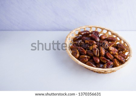 Dried dates on white background. Holy month of Ramadan, concept. Righteous Muslim lifestyle. Starvation. Dates in wooden basket. Vegetarian food. Copy space