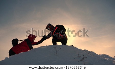 team work and victory. Tourists extends hand to friend that rises to top of hill. Climbers in winter on snowy mountain work in Kamanda helping to climb hill. sports tourism concept.