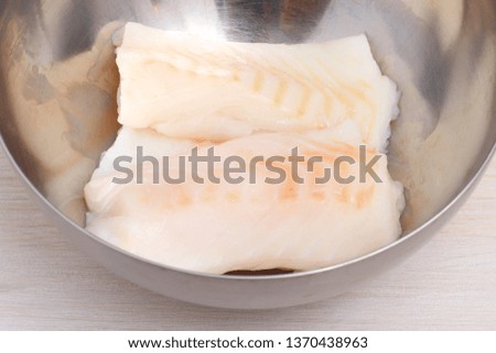 two a piece raw cod,  fish in a metal bowl