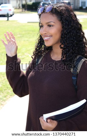 Columbus,Ohio/USA March 24, 2019:  Young College student carrying a book while waving to a friend. Royalty-Free Stock Photo #1370440271