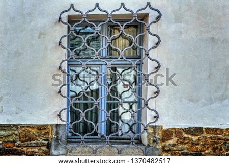 A window covered with traditional decorative iron grid.