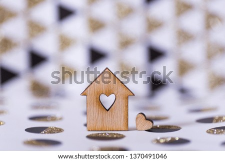 Closeup wooden house with hole in form of heart on geometric abstract background with golden glitter. Concept of sweet home, copy space