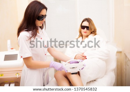 Skin Care. Hair removal on the legs, laser procedure at clinic. Beautician removes hair on beautiful female legs using a laser