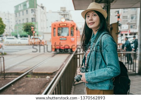 Young woman tourist using digital camera take pictures of train running on railway. elegant lady waiting for light subway arrive. smiling girl backpacker photographing travel sightseeing osaka city