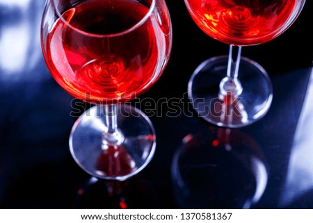 Two Glasses of red wine in bar, night club on black background with reflection.