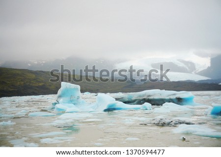 Beautiful blue glacier floating in the lagoon with Icelandic snow mountain and the mist in winter of Iceland 