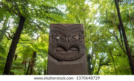 Tribe statue with fern trees in the background