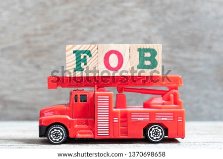 Red fire truck hold letter block in word FOB (Abbreviation of free on board) on wood background
