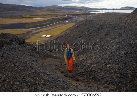 Happy tourist woman in bright clothes and yellow coat , enjoying traveling Iceland
