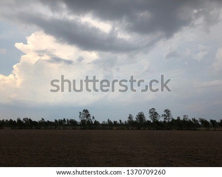 Dark clouds and sky in the field background.Dark storm clouds in rural garden.Before rain in Rice field.