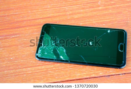 Black smartphone with a broken screen on a wooden table