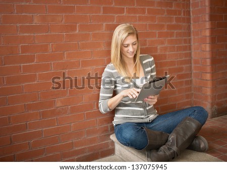 Pretty young woman using tablet computer studying