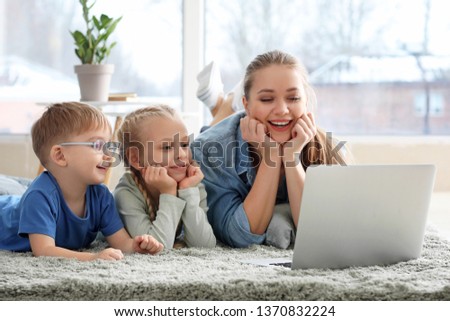 Young mother with little children watching cartoons at home