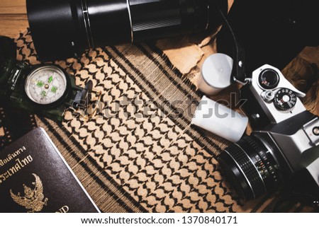 Retro camera film compass and thailand passport with shemagh scarf on wooden table. travel equipment. copy space.