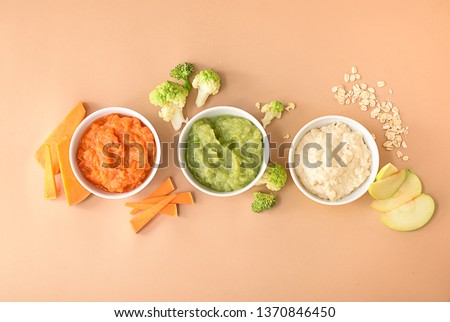 Bowls with healthy baby food on color background Royalty-Free Stock Photo #1370846450
