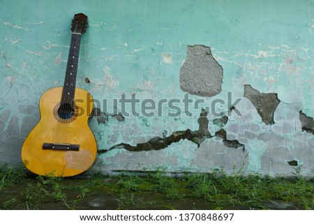 the brown guitar clings to the old blue painted wall