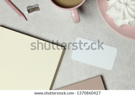 The mockup business card with the note book paper, a pink cup of coffee, the wooden pencil & sharpener
