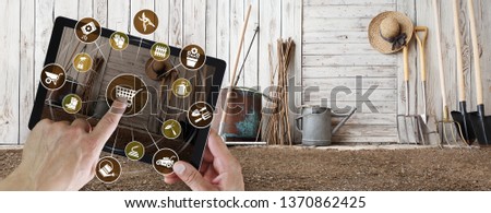 gardening equipment e-commerce concept, online shopping on digital tablet, hand pointing and touch screen with garden tools icons, tool shed in the background