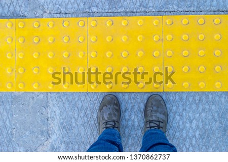 Woman feet near block tactile paving for blind handicap. Tactile paving for blind handicap on tiles pathway, walkway for blindness people. 