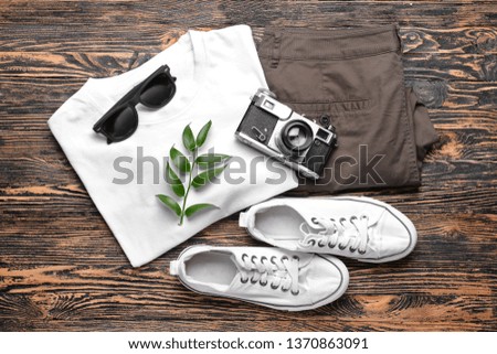 Male clothes with photo camera and sunglasses on wooden background