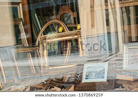 Closeup view of window showcase antique shop with old wooden frames for paintings and mirrors
