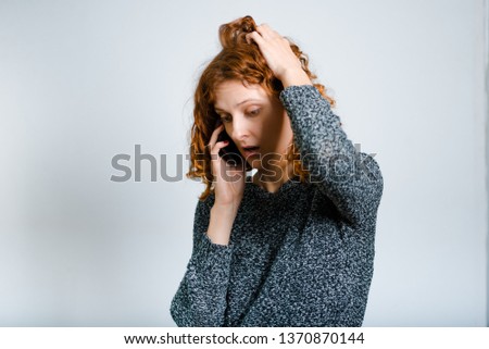 beautiful curly woman received bad news by phone isolated on gray background