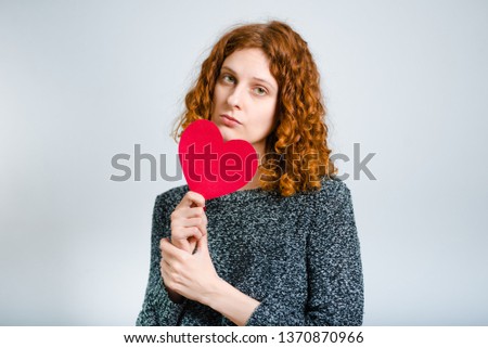 beautiful curly woman with a paper heart - love, isolated on gray background