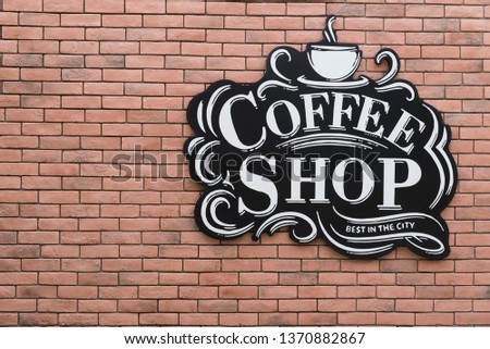 Coffee shop logo hang on a red brick wall.