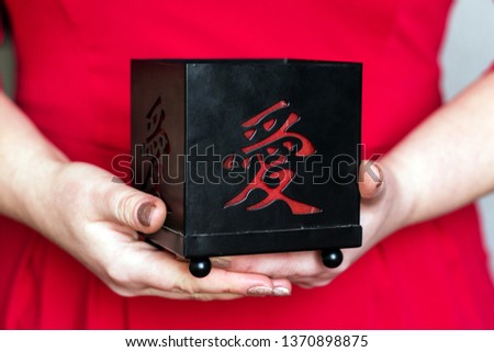 A woman in a red dress holding a black candle with a Japanese kanji love symbol. Love, relationship or valentines day concept.