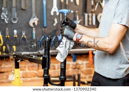 Man disassembling shock absorber of a bicycle fork at the workshop, close-up view