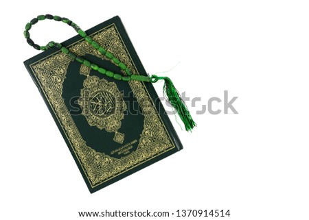 Quran and green rosary beads isolated on white background. Arabic word translation : The Holy Al Quran (holy book of Muslims). Islamic concept with copy space.