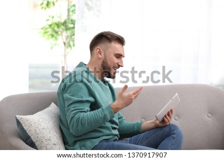 Young man using video chat on tablet in living room
