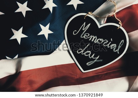 Overhead picture of black heart including the text Memorial day inside, on united states flag, vintage style