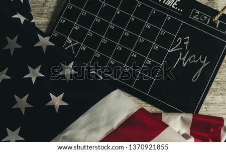 Overhead picture of calendar under united states flag, indicating the date 27 May 2019 in the calendar, all on wooden table, vintage style